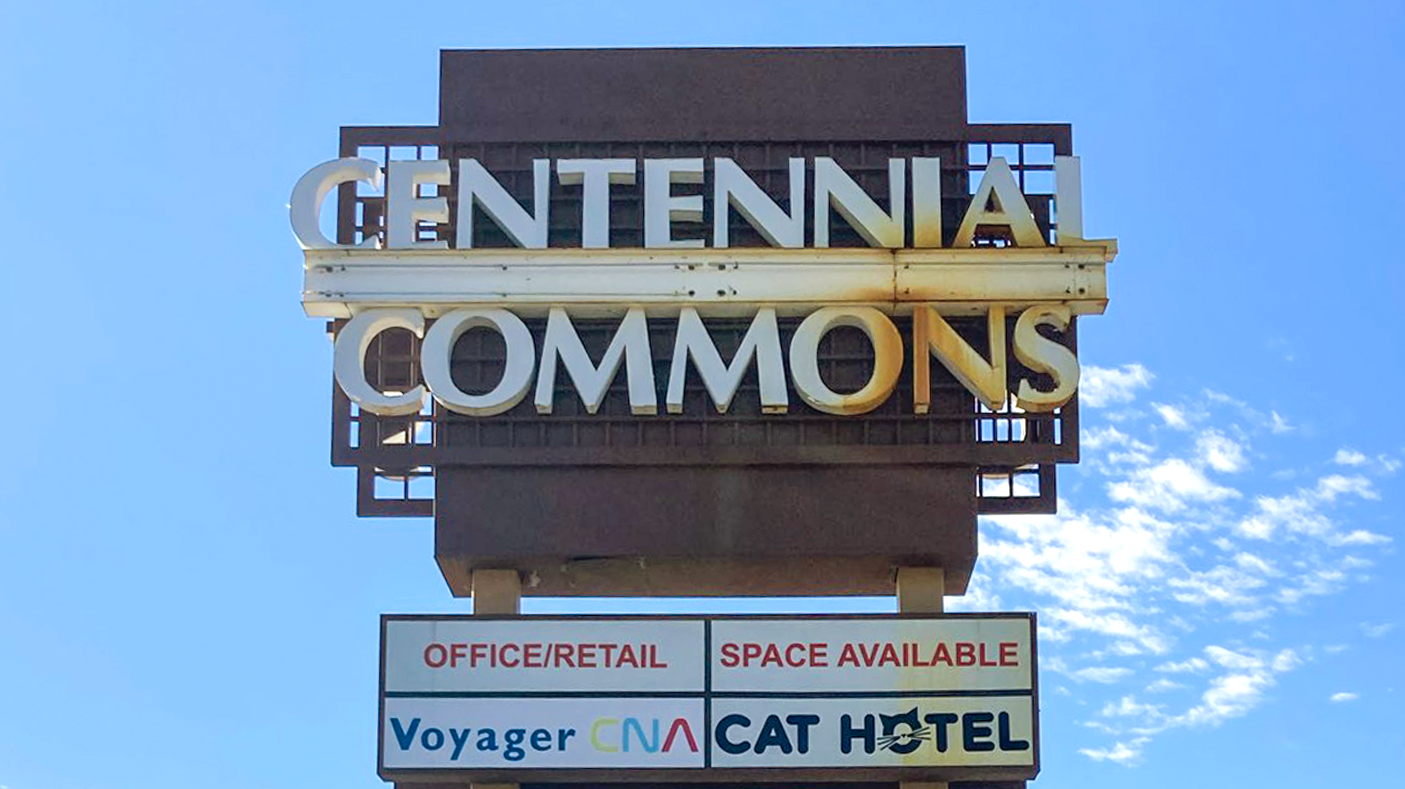 A front lit monument sign with rust damage shown during the day.